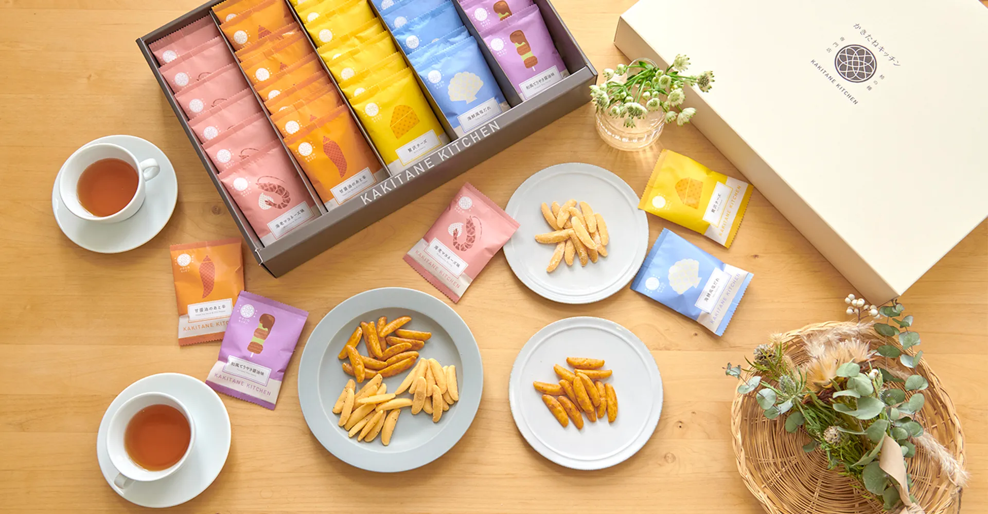 「かきたねキッチン」のカラフルなギフトボックスと、皿に盛られた柿の種。在庫管理自動化の事例。